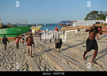 Zanzibar, Tanzanie - le 16 février 2008 : African débardeurs décharger un bateau de bois d'oeuvre dans le port de Zanzibar. Banque D'Images