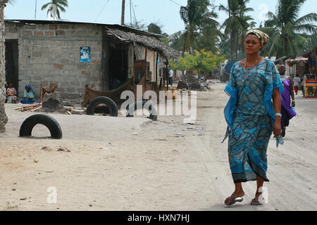 Zanzibar, Tanzanie, 18 février 2008 : African woman walking le long de la route poussiéreuse du village de pêche côtière. Banque D'Images