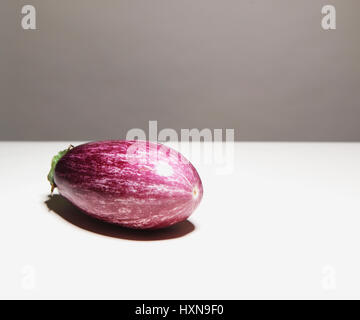 Aubergine pourpre variated unique, réduit de moitié, sur la surface blanche et fond gris Banque D'Images