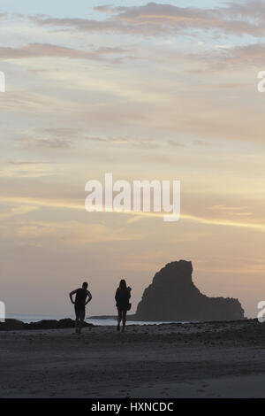 Waling couple sur une plage pendant la golden sunset Banque D'Images