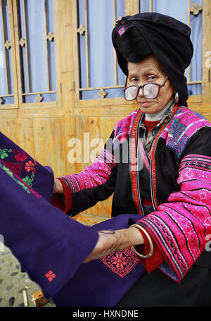 La province de Guangxi, Chine - 4 avril : vieille femme de grands verres, Yao rouge nationalité, les groupes de minorités ethniques en Chine, tenant un tissu bleu avec des motifs Banque D'Images