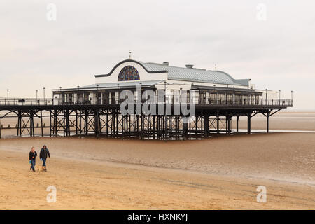 Bridport, England - 14 mars : l'homme et la femme marcher un chien sur la plage cleethorpes avec jetée en arrière-plan. Dans Bridport, England. le 14 m Banque D'Images