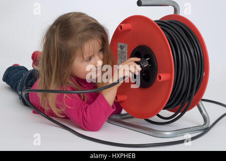 Fillette de quatre ans joue avec tambour de câble et câble électrique, vierjähriges Mädchen spielt mit und Kabeltrommel Stromkabel Banque D'Images