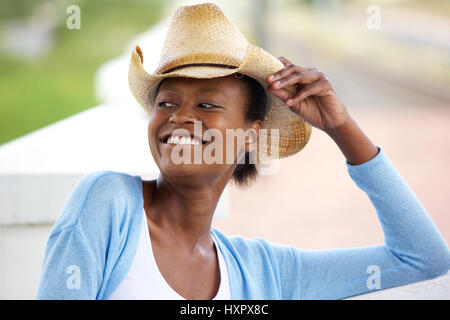 Close up portrait of smiling young African woman with cowboy hat looking away Banque D'Images