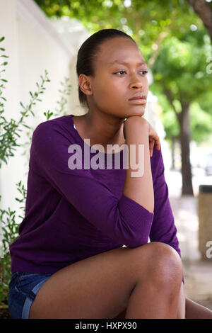 Portrait de jeune femme africaine pensif assis seul à l'extérieur Banque D'Images