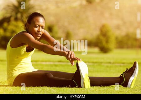 Portrait de jeune femme noire runner stretching jambes dans le parc Banque D'Images