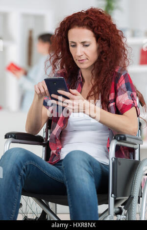 Femme handicapée dans un fauteuil roulant sur le téléphone Banque D'Images