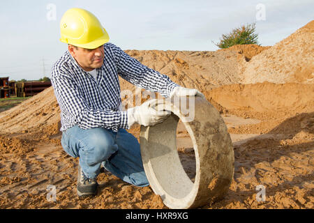 Travailleur de la construction travaille avec tuyau, Bauarbeiter arbeitet mit Rohr Banque D'Images