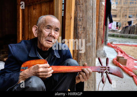 Zhaoxing Village Dong, province de Guizhou, Chine - 9 Avril 2010 : les hommes d'Asie Personnes âgées autochtones Dong, jouant à l'échelle locale des instruments de musique à cordes s'asseoir Banque D'Images