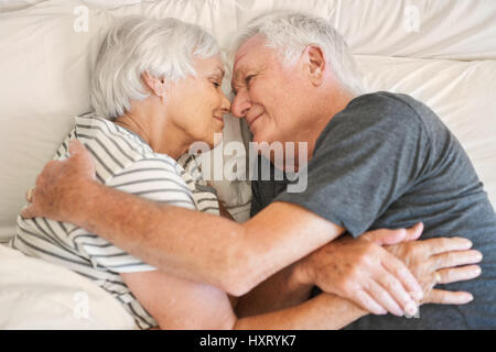 Happy senior couple smiling chaudement l'un l'autre dans le lit Banque D'Images