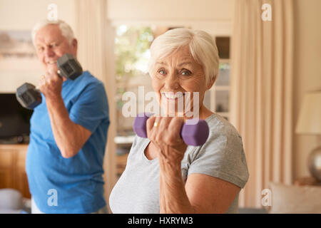 Smiling senior couple dumbells de levage ensemble à la maison Banque D'Images