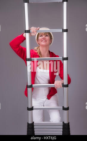 Woman climbing une échelle télescopique en aluminium Banque D'Images