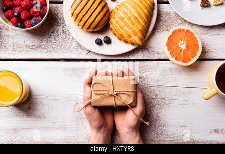 La fête des Mères, la composition. Mains de méconnaissable woman holding petit cadeau. Repas Petit déjeuner. Studio shot on white background. Banque D'Images