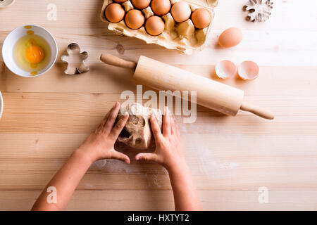 La fête des Mères, la composition. Mains de méconnaissable girl baking cookies, jouer avec la pâte. Studio shot sur fond de bois. Banque D'Images