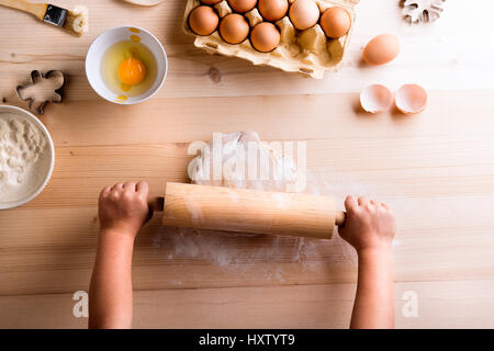 La fête des Mères, la composition. Mains de méconnaissable girl baking cookies, rouler la pâte sur la table. Studio shot sur fond de bois. Banque D'Images