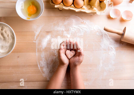 La fête des Mères, la composition. Mains de méconnaissable girl holding pastry heart. Studio shot sur fond de bois. Banque D'Images