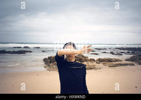 Femme avec les yeux fermés sur peint sur son bras debout sur la plage, derrière la mer, Afrique du Sud Banque D'Images