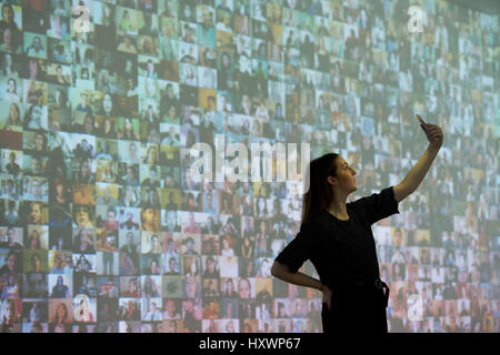 Un visiteur prend une en face de selfies à grande échelle l'installation audio-visuelle intitulée "Hello World !", 2008, par Christopher Baker lors d'une presse à l'aperçu de Selfies Créations pour l'exposition à la Saatchi Gallery de Londres, qui étudie l'histoire de l'intermédiaire de selfies artistes portrait de la vie d'autoportraits. Banque D'Images