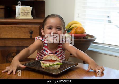 Jeune fille posant avec un sandwich à la table Banque D'Images