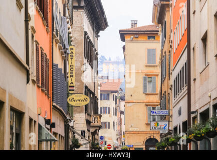 Trento, Italie - 21 mars 2017 : des maisons dans une rue étroite de la vieille ville avec différentes façades, des cafés et des enseignes. Banque D'Images