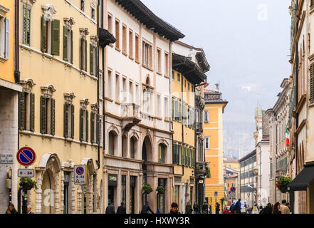 Trento, Italie - 21 mars 2017 : les gens dans une rue commerçante de la vieille ville avec des maisons aux façades variées, des cafés et des boutiques. Banque D'Images