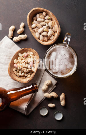 Lager beer mug, bouteille et des collations sur table en pierre. Divers écrous. Vue d'en haut Banque D'Images