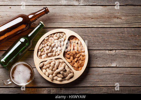 La bière, bouteilles en verre et en-cas sur table en bois. Divers écrous. Top View with copy space Banque D'Images