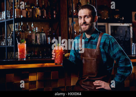 Portrait d'un hipster barman avec barbe smiling sitting en bar. Banque D'Images
