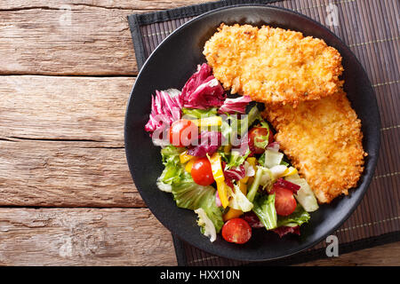 Steak de poulet dans la chapelure Panko et salade fraîche sur la table horizontale vue du dessus. Banque D'Images