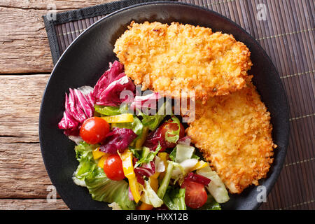 Steak de poulet dans la chapelure Panko et salade de légumes frais sur la table horizontale vue du dessus. Banque D'Images