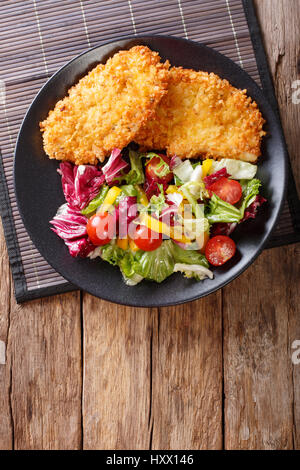 Steak de poulet dans la chapelure Panko et salade fraîche sur la table. Vue verticale d'en haut Banque D'Images