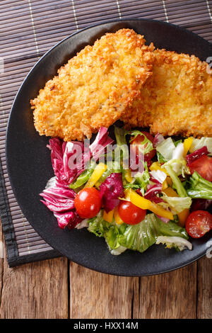 Steak de poulet dans la chapelure Panko et salade de légumes frais sur la table. vertical Vue de dessus Banque D'Images