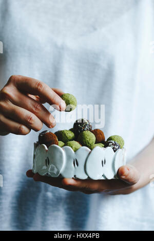 Une femme tenant un bol de matcha mixtes et des desserts au chocolat Banque D'Images