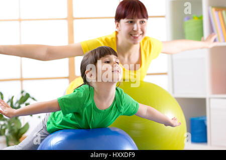 Mère de faire la gymnastique avec fille kid on fitness ball Banque D'Images