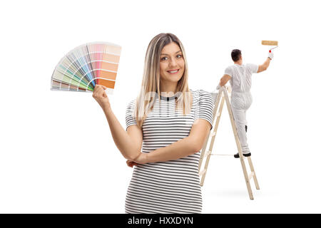 Jeune femme tenant un échantillon de couleur de peinture avec un peintre a grimpé sur une échelle isolé sur fond blanc Banque D'Images