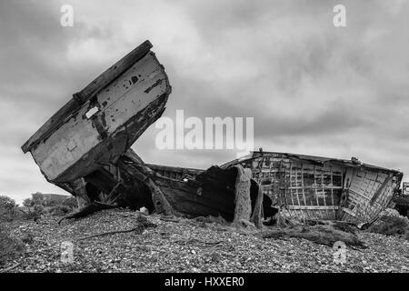 L'épave d'un vieux bateau de pêche en bois sur la plage de galets à Dungeness, Kent, Angleterre, Royaume-Uni. Version noir et blanc Banque D'Images