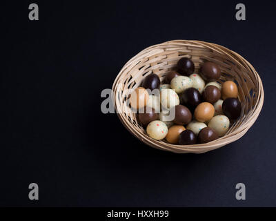 Oeufs de Pâques en chocolat panier en bois isolé sur fond noir Banque D'Images