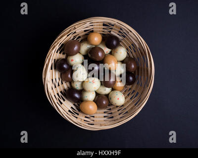 Oeufs de Pâques en chocolat panier en bois isolé sur fond noir Banque D'Images