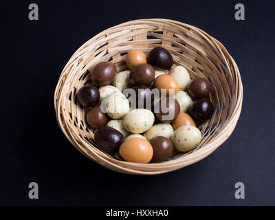 Oeufs de Pâques en chocolat panier en bois isolé sur fond noir Banque D'Images