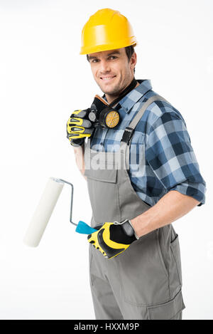 Smiling workman in protective workwear holding paint roller Banque D'Images