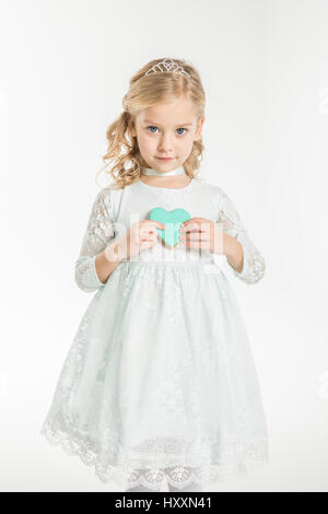 Cute little girl holding heart shaped cookie et looking at camera Banque D'Images