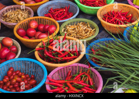 Variété de poivrons colorés, les tomates, le gingembre et les verts dans des paniers en vente au marché du matin locales à Sattahip, Thaïlande Banque D'Images