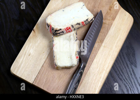 Couper le fromage taleggio italien sur planche à découper en bois avec couteau - Lombardie avec fromage typique arôme fort, mais sa saveur est douce avec un fruité tang Banque D'Images