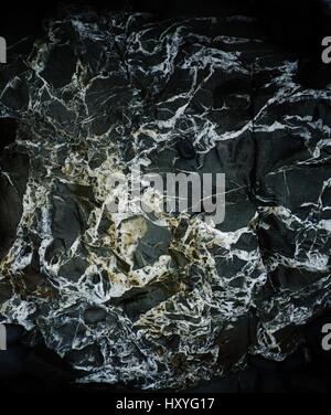 Un rock noir humide avec un quartz de persillage trouvés sur une plage de North Cornwall, Angleterre, Royaume-Uni. Banque D'Images