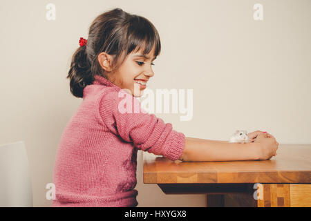 Happy girl in pink jouer avec son hamster curieux Banque D'Images