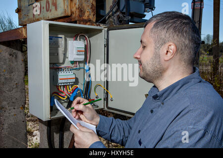 Une sous-station électrique, ingénieur électricien l'écriture Lecture de compteur d'électricité sur le Presse-papiers. Banque D'Images