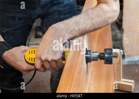 L'installation de porte, serrure de porte installation, l'utilisation d'une scie pour commencer à couper le trou pour serrure à pêne dormant, close-up carpenter détient la main perceuse électrique jaune. Banque D'Images