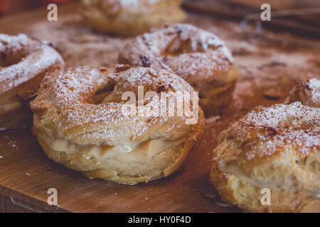 Profiteroles fraîchement rempli de crème vanille et recouvert d'amandes rôties sur planche de bois rustique, Close up Banque D'Images