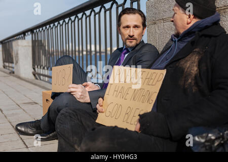 Deux hommes assis sur le trottoir du désespoir Banque D'Images