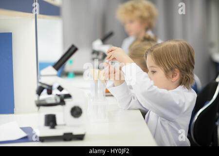 Petit garçon réglage vide les tubes à essai en laboratoire scientifique. Banque D'Images